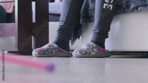 Kid wears old women's slippers, and sitting on couch photo