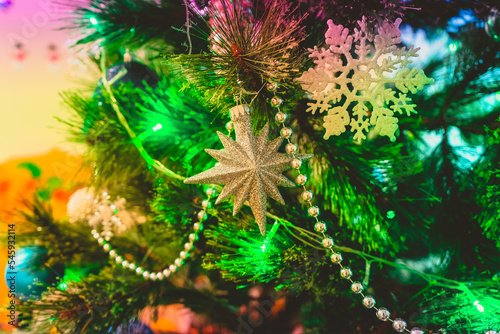 the Christmas tree is decorated with stars  snowflakes  balls  beads and a glowing electric garland in a magical light