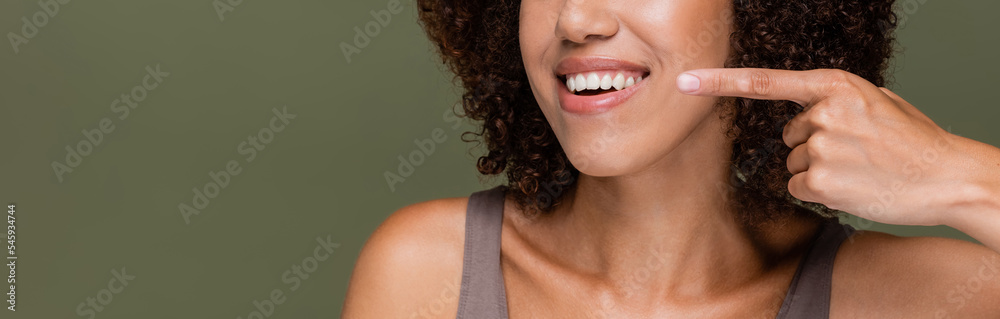 Naklejka premium Cropped view of african american woman pointing with finger isolated on green, banner.