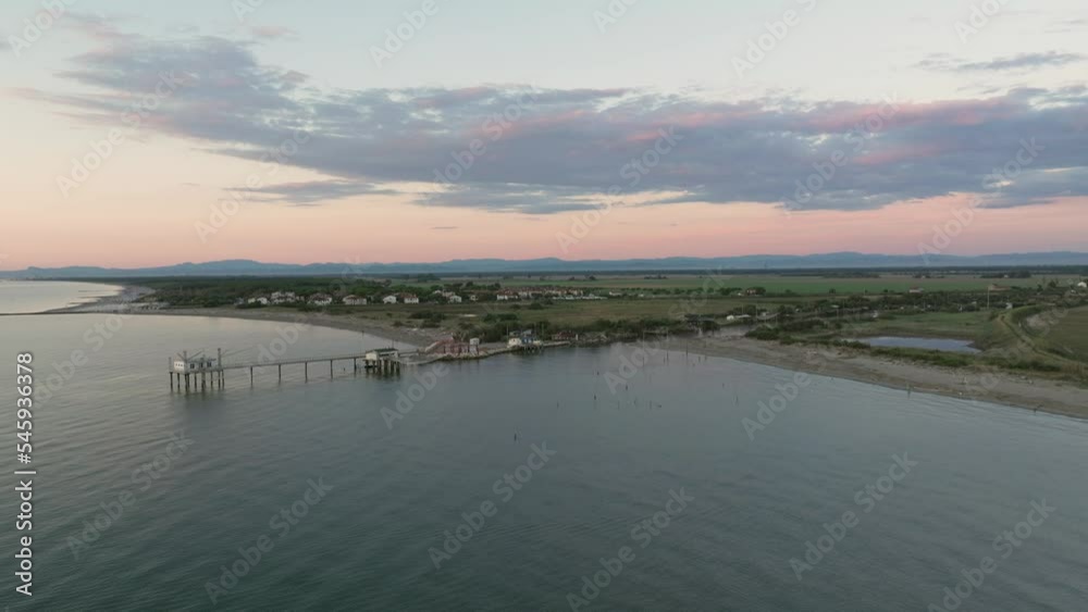 Aerial view slow motion of fishing huts on shores of estuary at sunset,italian fishing machine, called Aerial view slow motion of fishing huts on shores of estuary at sunset,italian fishing machine, called
