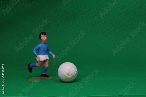 Football Soccer figure in blue and white , with black football boots ,   Football player and football on green background, vintage toy from 1970s -1980s, Soccer action figure. 