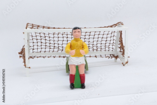 Goal keeper , Football Soccer figure in yellow and white kit in front of the goal ,   Football player and football, vintage toy from 1970s -1980s, Soccer action figure. 