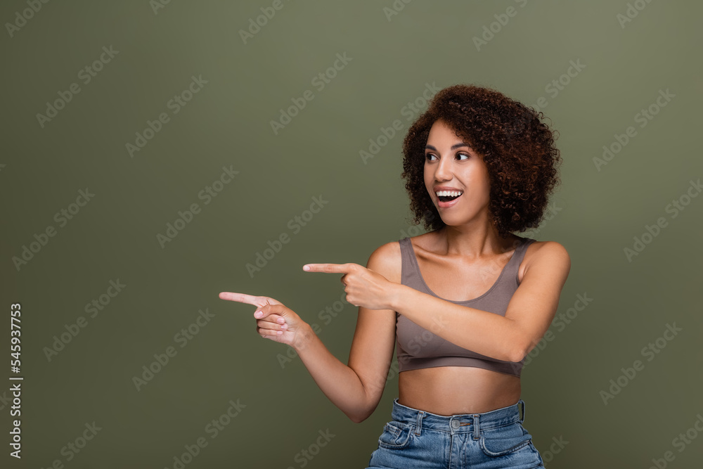 Smiling african american woman pointing with fingers isolated on green. Smiling african american woman pointing with fingers isolated on green.