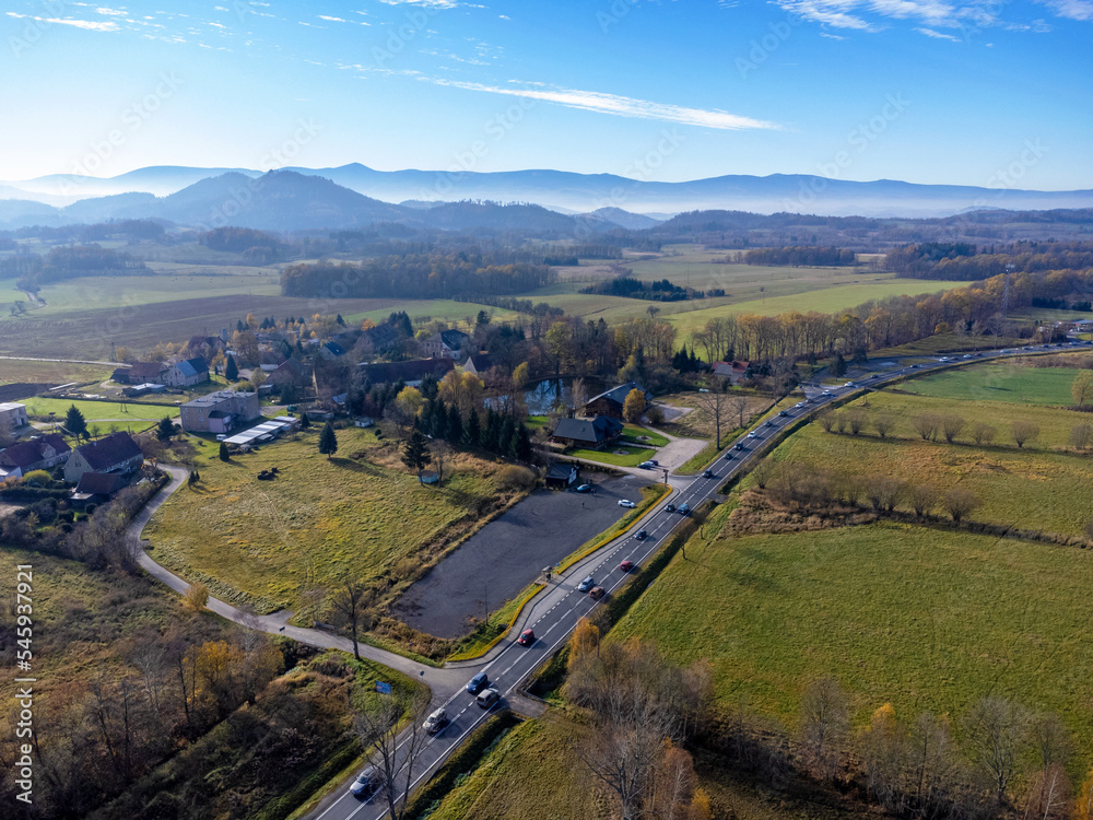 Aerial view of charming small town in Poland. Mountains with fall multicolor trees and beaufitul sky.
