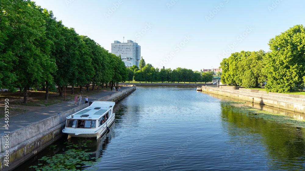 View of embankment of Pregolya river and House of Soviets. Unfinished building in the center of the city of Kaliningrad, Russia. Pleasure river boat