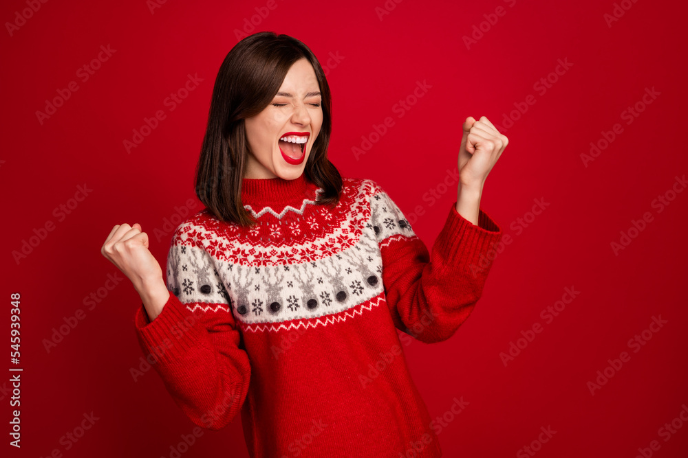 Portrait of excited satisfied woman with bob hairdo wear red sweater eyes closed raise fists scream yeah isolated on red color background
