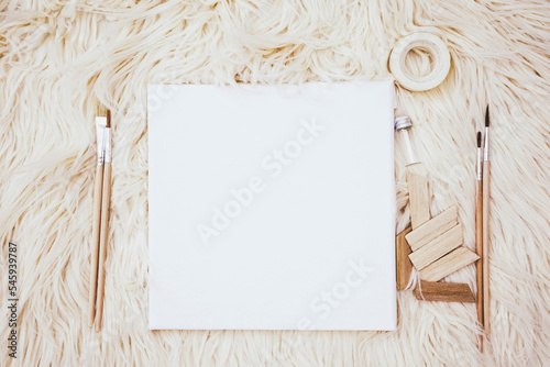 Art flat lay in neutral tones with a white canvas, brushes and other arty stuff