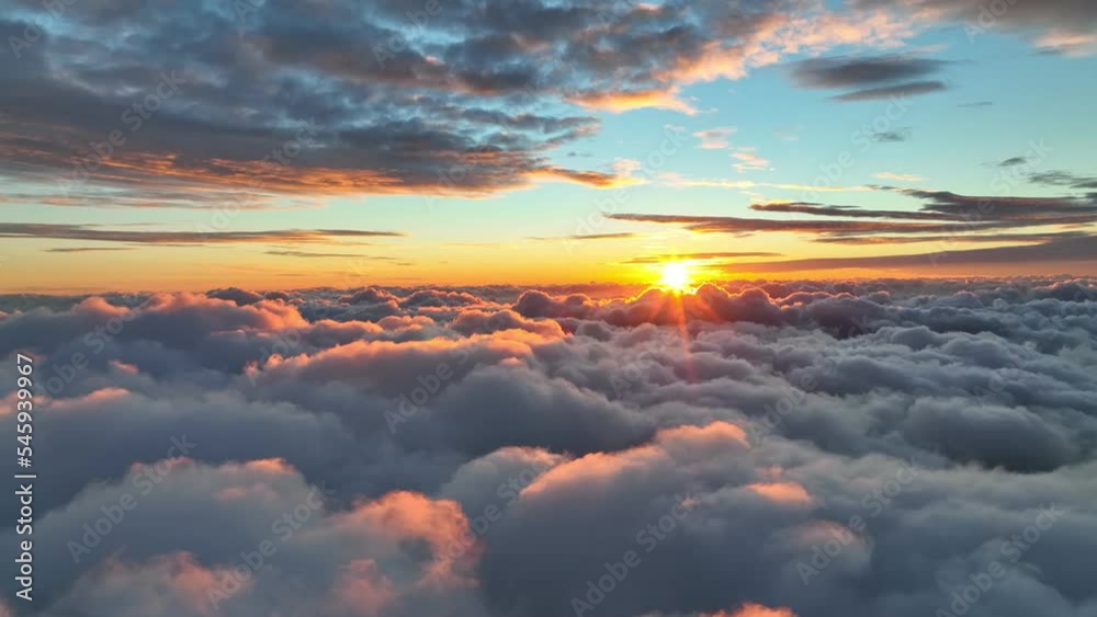 Epic sunset over the clouds. Warm sun sets over the horizon in clouds. Flight in the sky at sunset, view from window of airplane. UHD, 4K