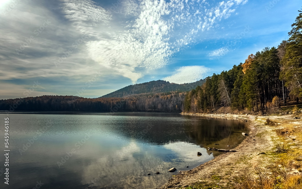 Autumn landscape with lake shore, mountains and sky with clouds