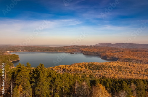 Autumn landscape from the top of a mountain with a lake, trees, mountains and sky