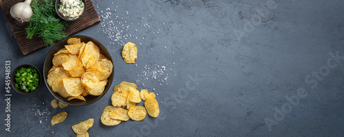 Potato chips with onions, dill and sour cream on a graphite background. Top view, copy space.