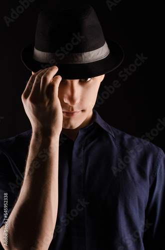 Portrait of a young man in a hat with a ribbon, close-up, on a black background © Anna