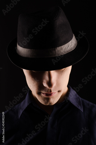 Portrait of a young man in a hat with a ribbon, close-up, on a black background © Anna