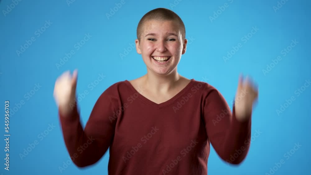 Successful winner young gender fluid non binary woman 20s looks at camera isolated on blue background studio portrait Successful winner young gender fluid non binary woman 20s looks at camera isolated on blue background studio portrait