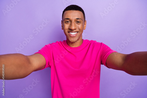 Portrait of satisfied pleasant handsome man with fade hairstyle wear pink t-shirt making selfie isolated on violet color background