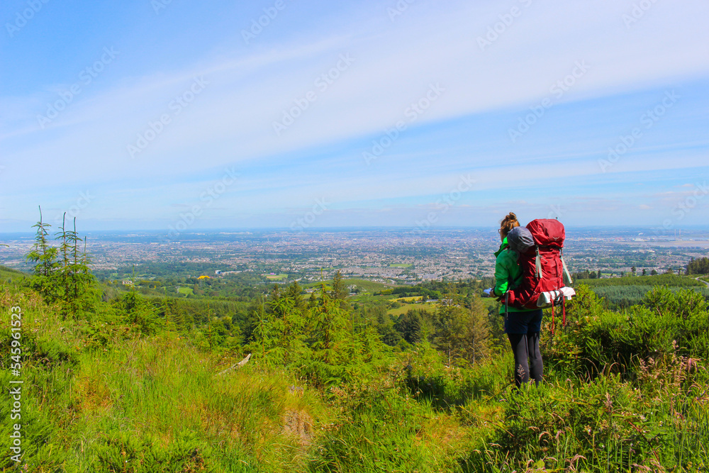 Woman with backpack is hiking in the wild mountains in Ireland Woman with backpack is hiking in the wild mountains in Ireland