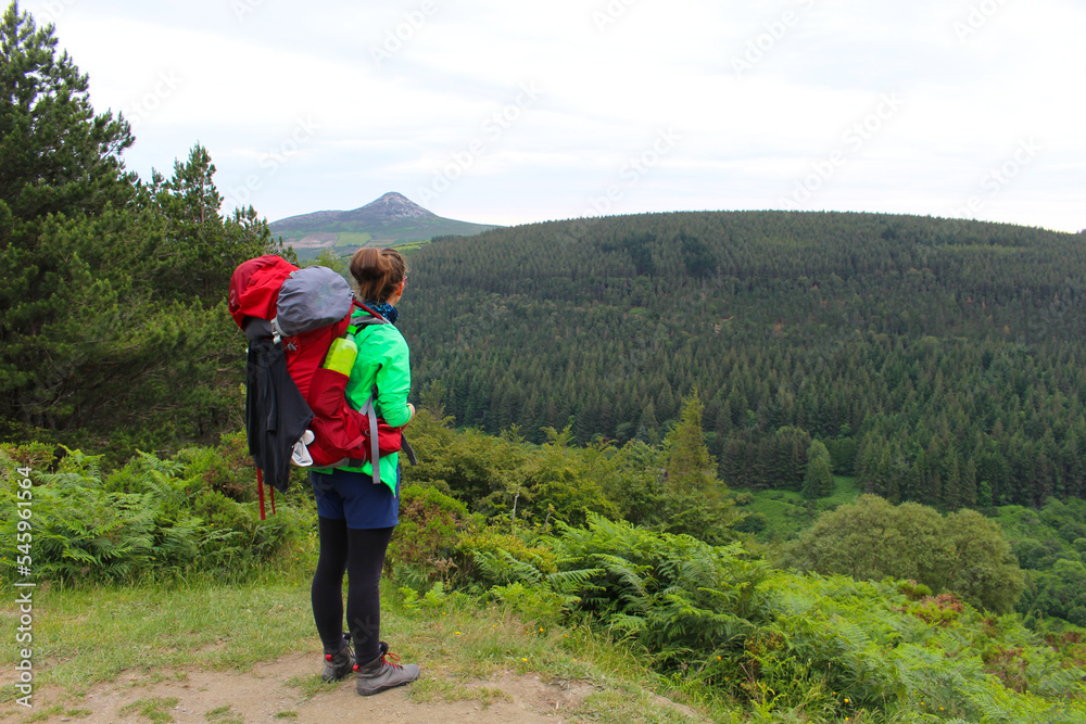 Woman with backpack is hiking in the wild mountains in Ireland