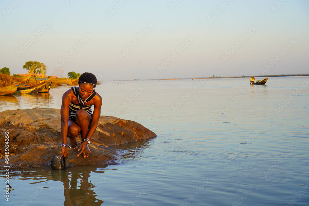 Beautiful African woman fetching water from the River  - obrazy, fototapety, plakaty 