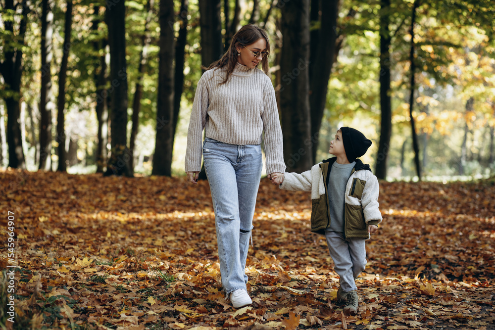 Mother with her little son walking in autumnal park Mother with her little son walking in autumnal park