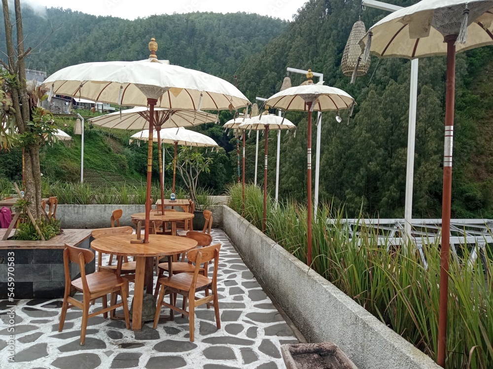 Wooden chairs and table with umbrella in the outdoor cafe