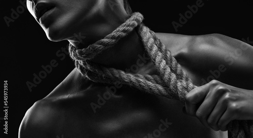 A young woman plucks ropes from her body and neck. Photo in black and white