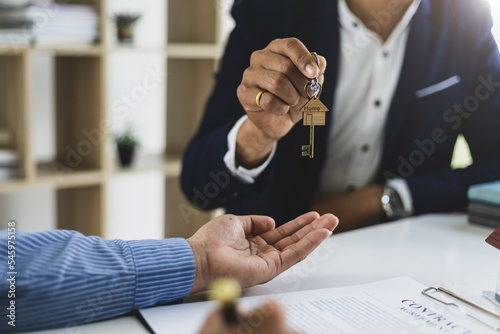Real estate agent hands over the house keys to a homebuyer after the purchase agreement has been signed.