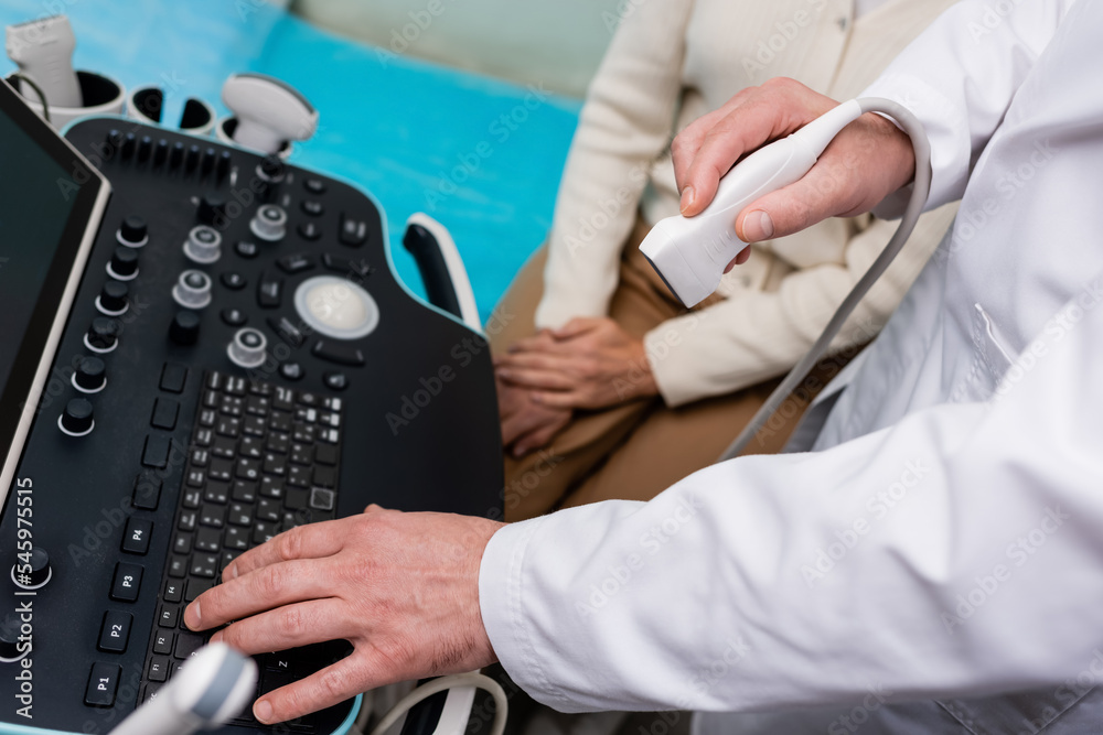 partial view of doctor using console of ultrasound machine near woman in clinic. partial view of doctor using console of ultrasound machine near woman in clinic.