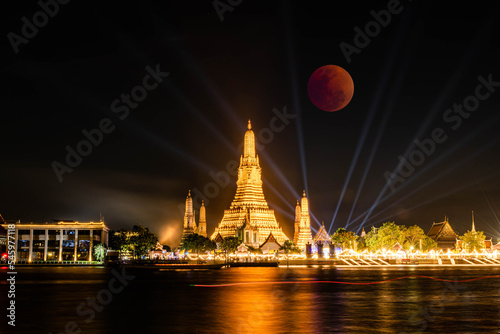 BANGKOK, THAILAND - November 8, 2022 : Lunar Eclipse, Super Red Full Moon taken from top side of “Wat Arun Temple”, This is a wonderful natural phenomenon with the view along Chao Praya River.