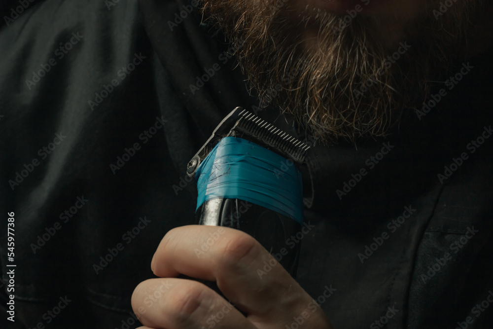 Naklejka premium shaving the beard with a broken clipper insulating tape