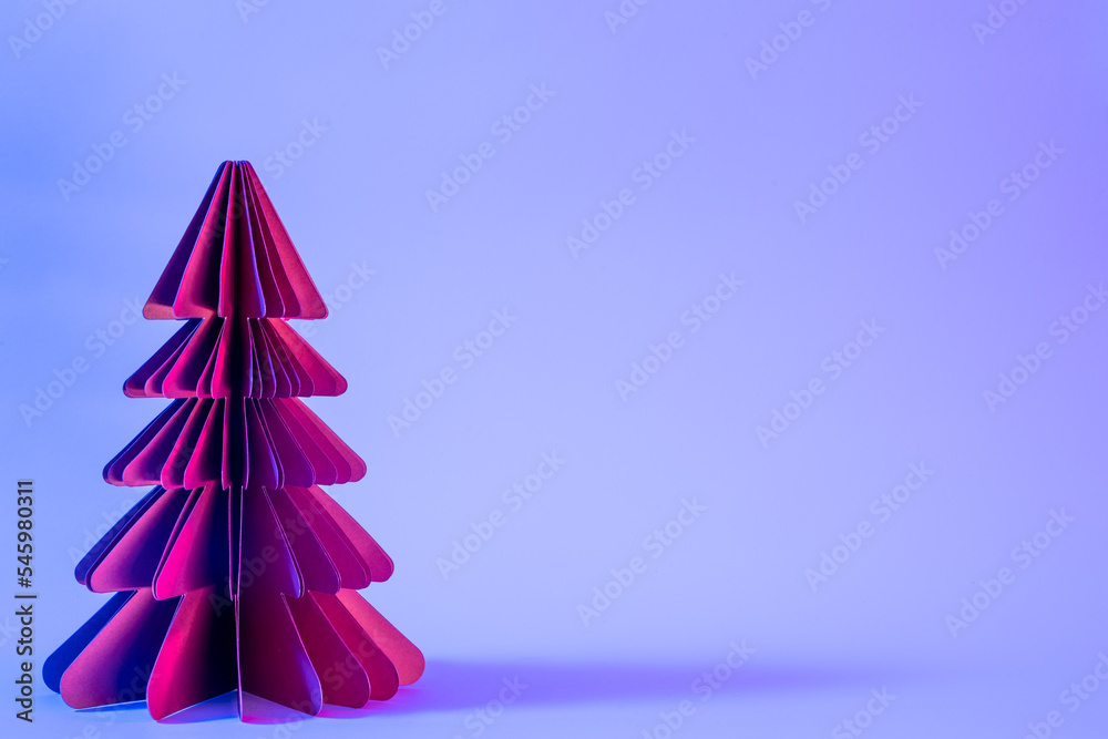 Decorative paper Christmas tree on blue background with trendy neon light.