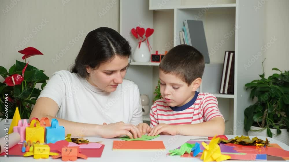Mother and son make crafts from paper, origami, create animal figurines. Mother and son make crafts from paper, origami, create animal figurines.