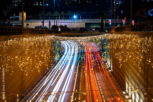 Modiin city's road with blue and red car lights and decorated with festive glowing garlands at night