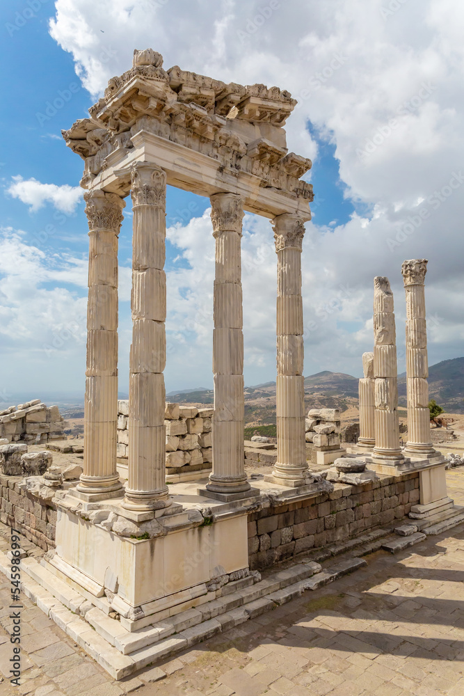 The ruined Temple of Trajan in Pergamon Ancient City. Corinthian order stone-cut relief on the frieze. Blue sky and scenic clouds at background. History, art or architecture concept. Bergama, Turkey