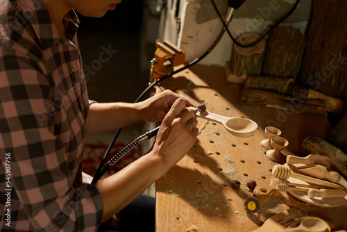 Female using power working tools graver for wooden utensils spoon