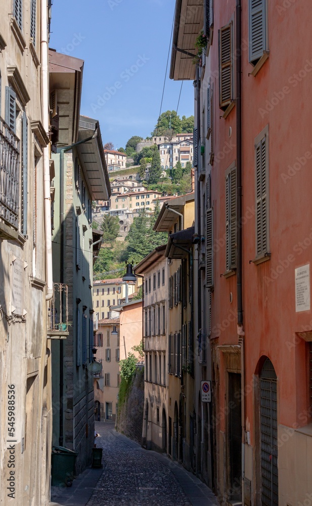 Vertical shot of an alley between buildings on a sunny day in Borgo Canale, Bergamo, Italy