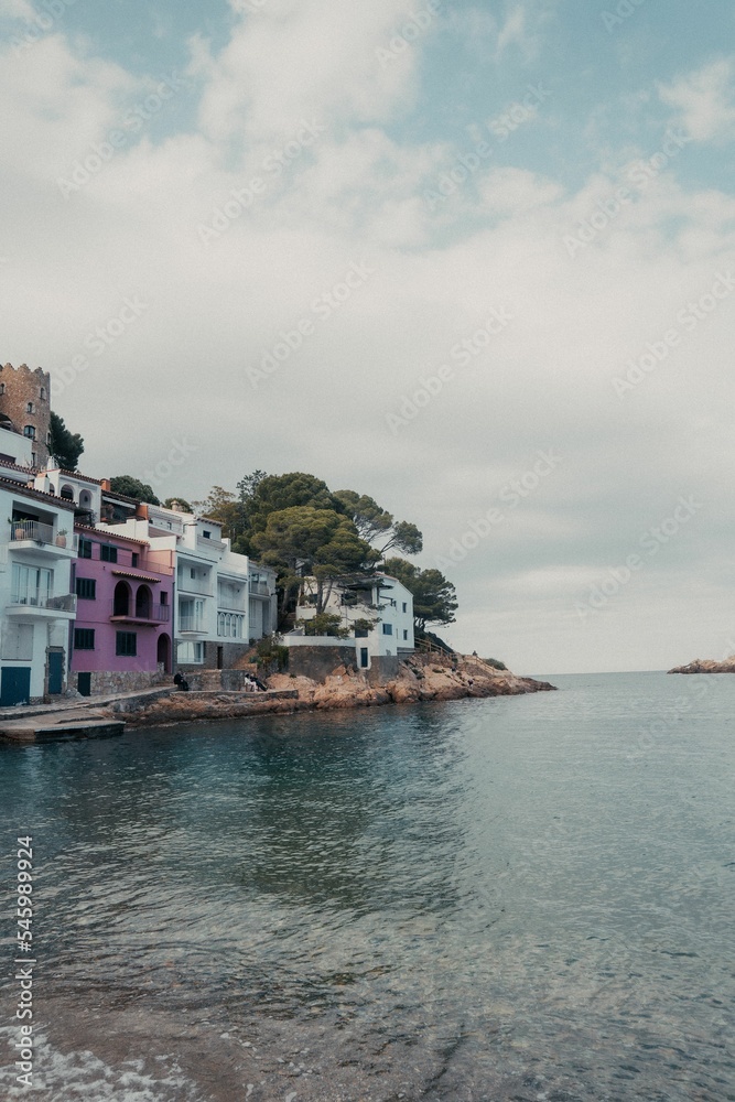 Naklejka premium Vertical shot similar houses near the stony beach on a clouded day