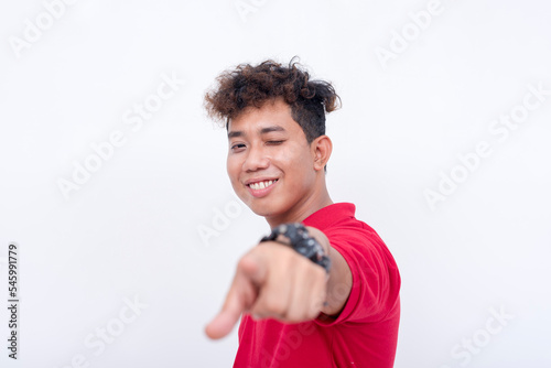 A confident and cocksure asian man points to the camera while winking. Isolated on a white background.