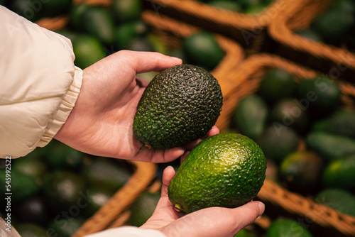 A woman chooses an avocado in a grocery store. photo