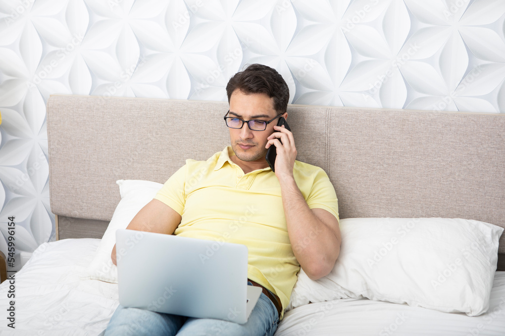 Handsome man lying on the bed and working on laptop Handsome man lying on the bed and working on laptop