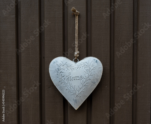 white heart with the inscription home hangs on a wooden brown background