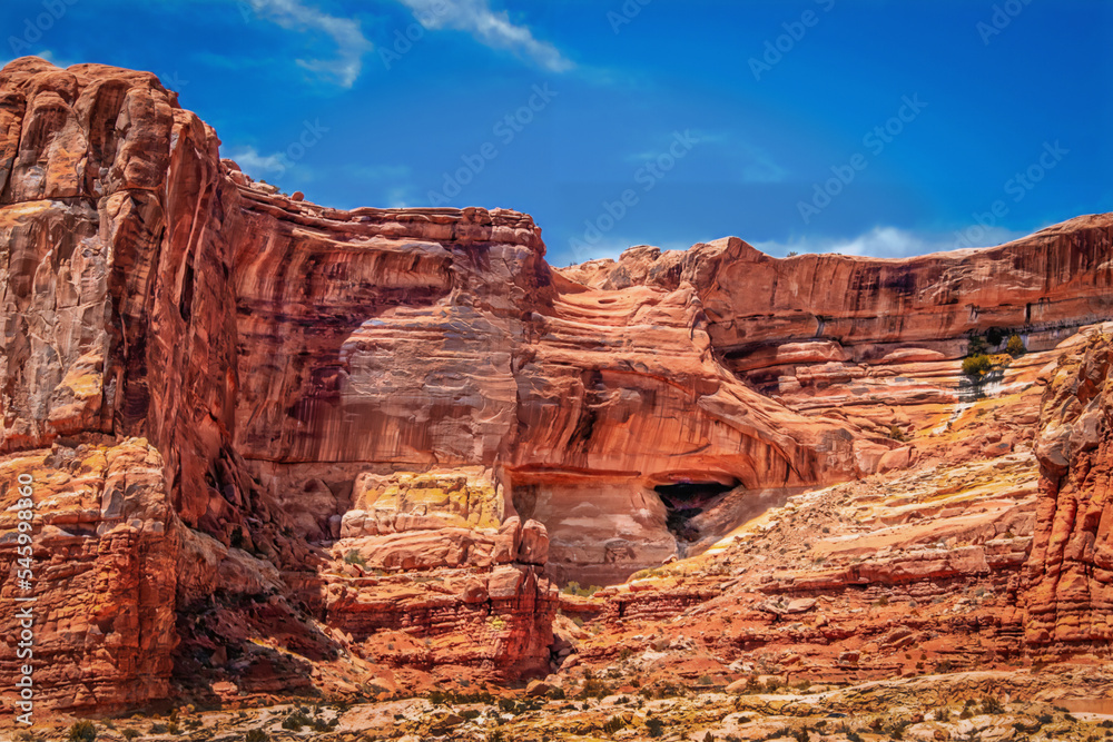 Red rock cliff near Arches National Park with crags and caves and layers jutting up into blue sky
