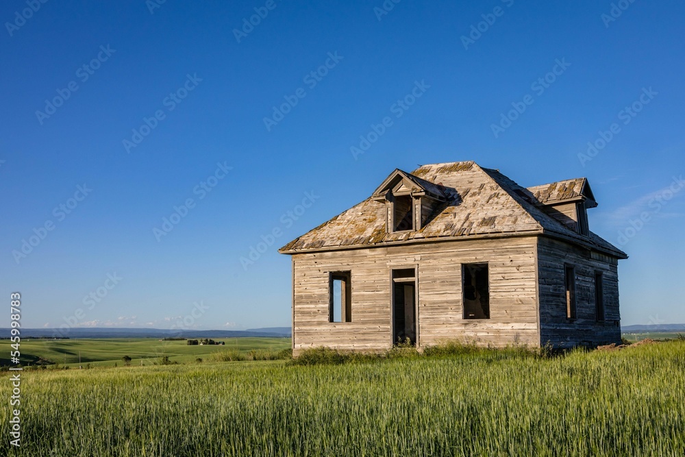 Long unused school house on farmland under the blue sky in Eastern Idaho, USA