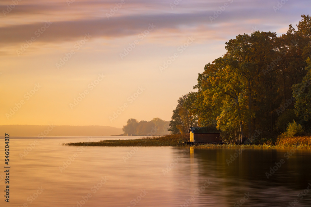 Einsames Bootshaus am Ufer des Plauer Sees in der Mecklenburgischen Seenplatte im Herbst zu Sonnenaufgang - obrazy, fototapety, plakaty 