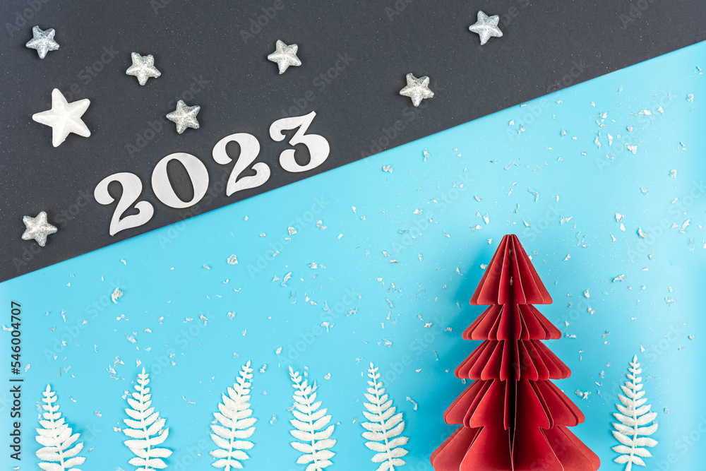 Obraz premium Christmas background with origami paper tree and number 2023, flat lay.