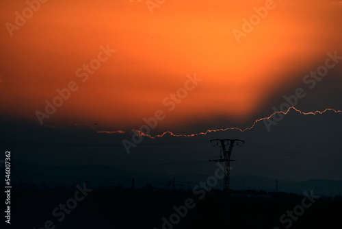 large high voltage tower at cloudy sunset with the sun hidden behind the clouds, albufera natural park valencia, spain