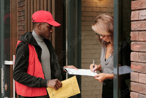 Foto Young black man in uniform holding envelope with letter while businesswoman with