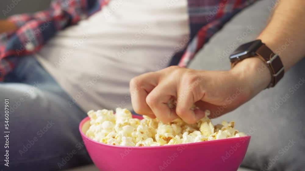 man eats popcorn and watches tv. Plate and hands close-up man eats popcorn and watches tv. Plate and hands close-up