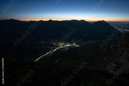 Bernese Oberland Highlands and Frutigen town light trails in the center at sunset photo