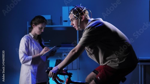 EEG topographer for examining brain, doctor making electrogram of scalp activity. Researching of brain work, man riding bicycle in electroencephalography headset. Rehabilitation after damage in sport. photo