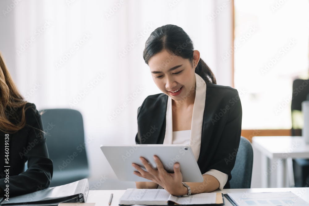 Bright and beautiful young Asian business woman happily at the office to come up with new ideas to work using a tablet smiling. Bright and beautiful young Asian business woman happily at the office to come up with new ideas to work using a tablet smiling.